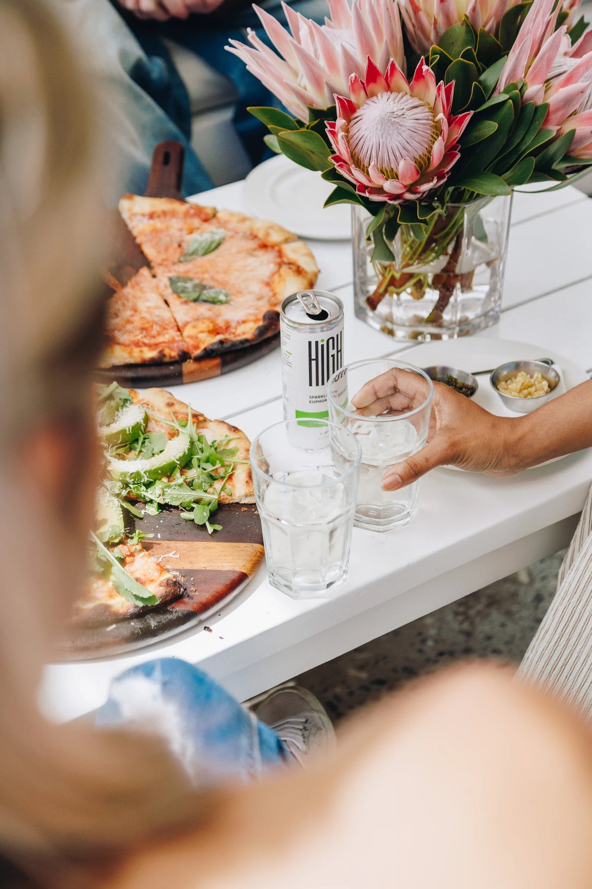 Yuzu Lemon HIGH on a lunch table with pizza and South African proteas